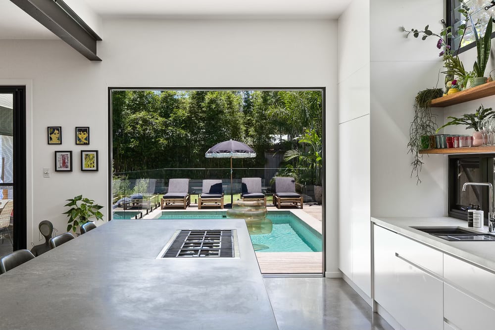 Modern Architect-designed house Caesarstone kitchen benchtop with large picture window looking out to pool