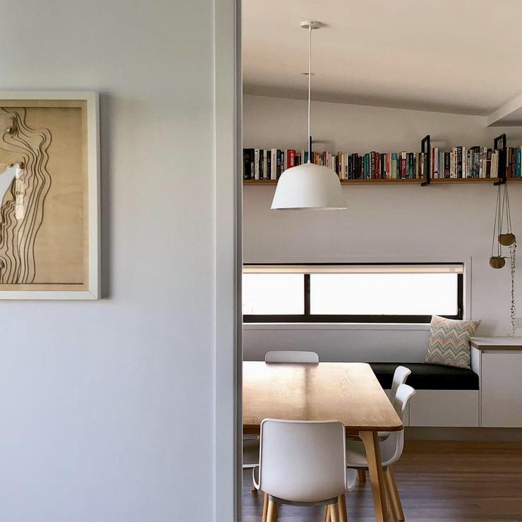 Renovated house with horizontal strip window, daybed below with bespoke shelving above with books.